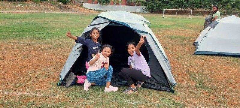 Three children sitting in a camping tent